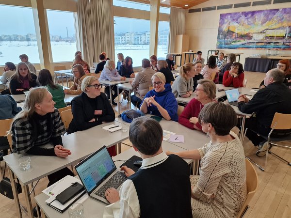Seminaari sisälsi myös työpajatyöskentelyä, jossa osallistujat rakensivat yhteiskehittelyn tilkkutäkkiä. Seminaarin osallistujat istuvat ryhmissä työpajatyöskentelyä varten.